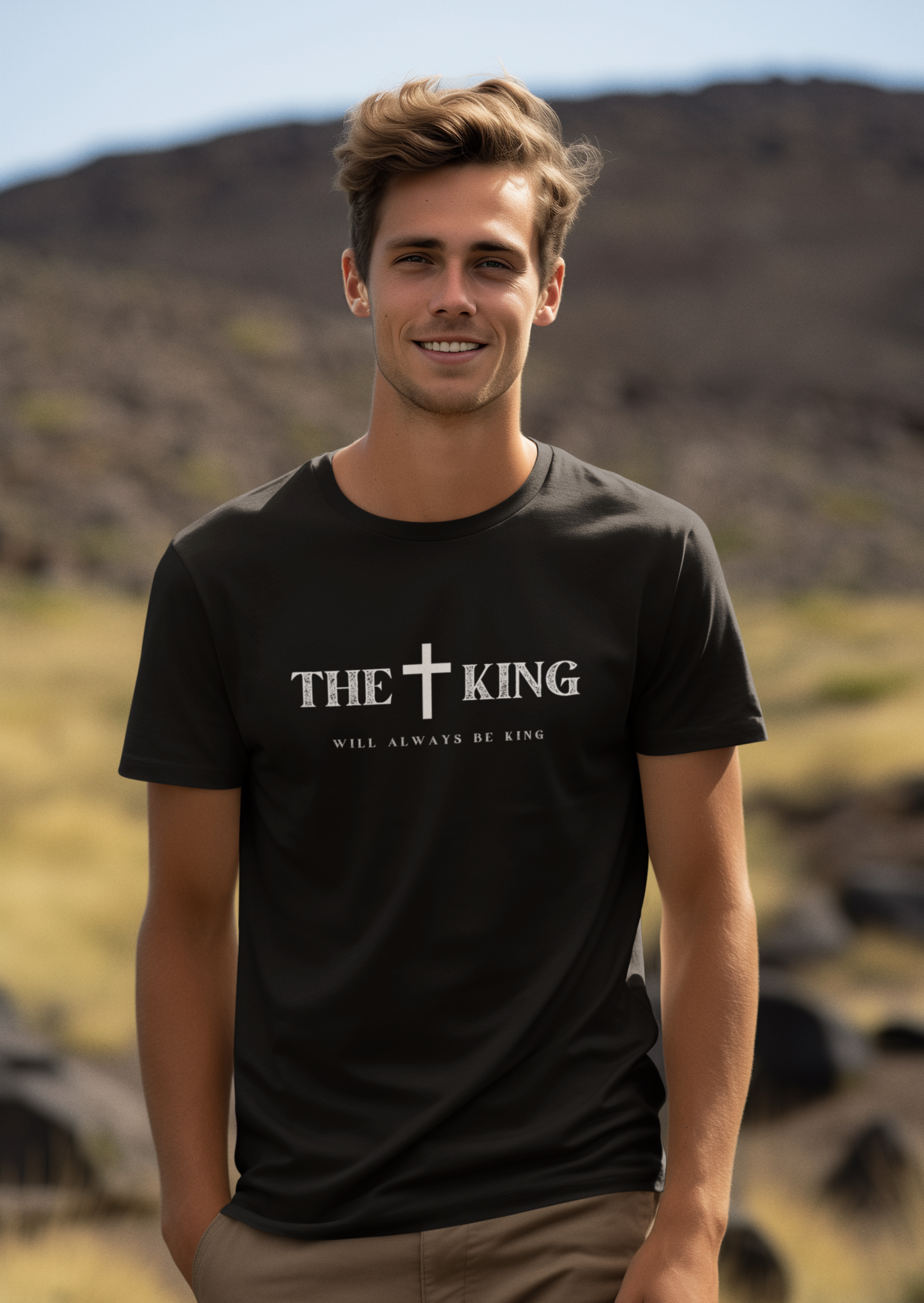 Man wearing a black t-shirt with 'The King Will Always Be King' text and cross symbol outdoors.