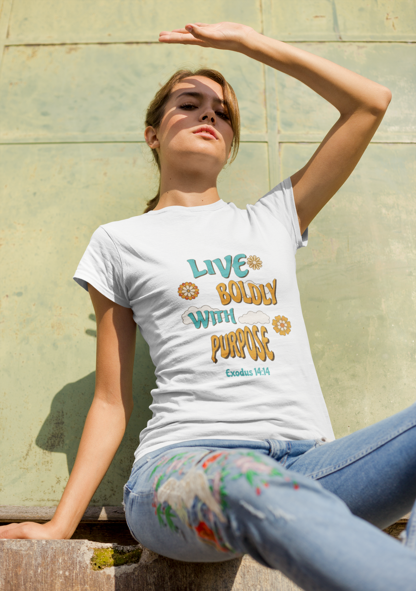 Woman wearing a white t-shirt with a motivational quote against a stone wall.