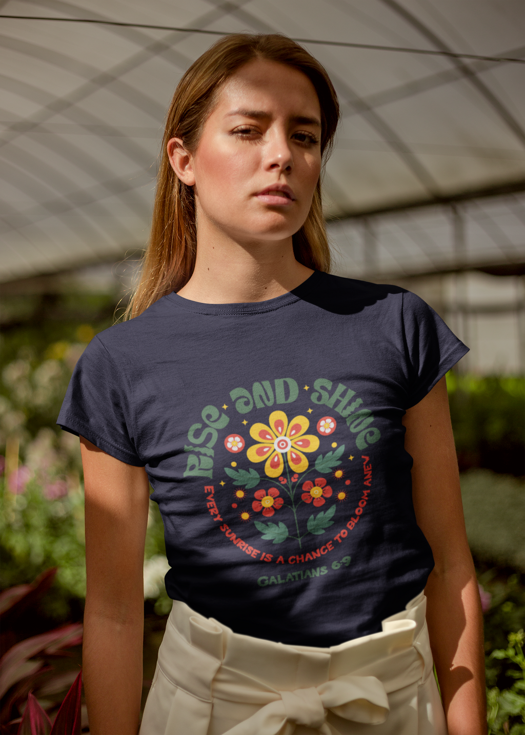 Woman wearing a dark blue t-shirt with a colorful graphic and text, standing outdoors.