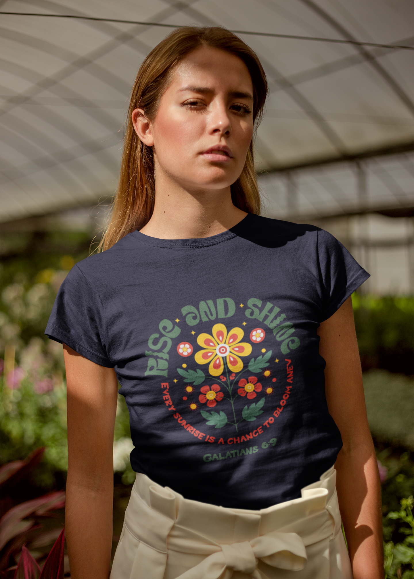 Woman wearing a dark blue t-shirt with a colorful graphic and text, standing outdoors.